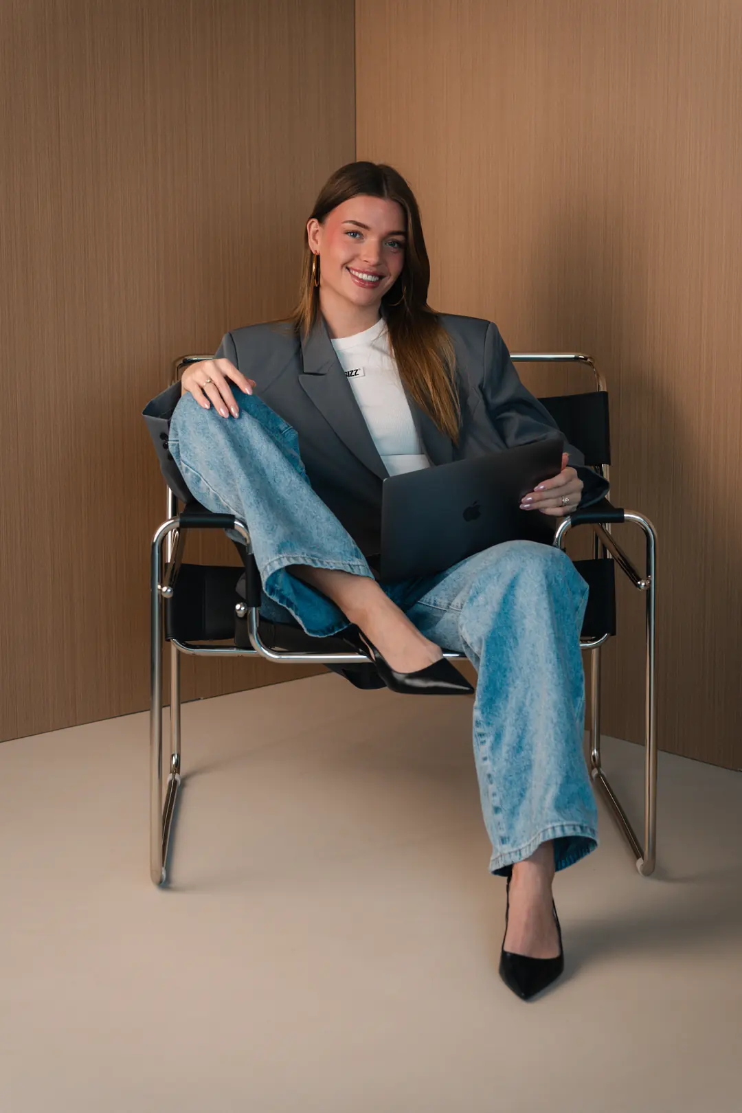 Eline Vera van Elive Creative, lachend in een zwarte design stoel met laptop